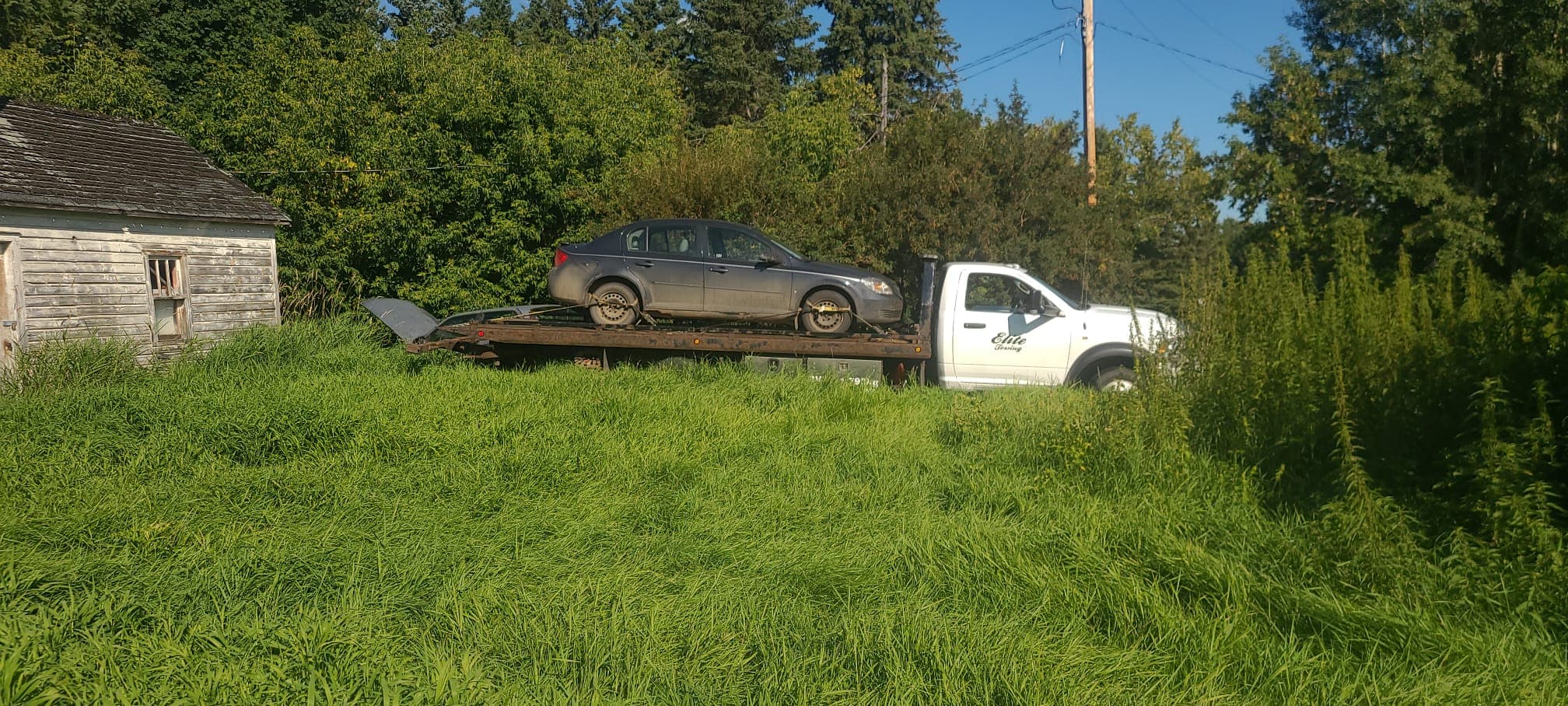Tow truck loading a car from a rural property near Edmonton