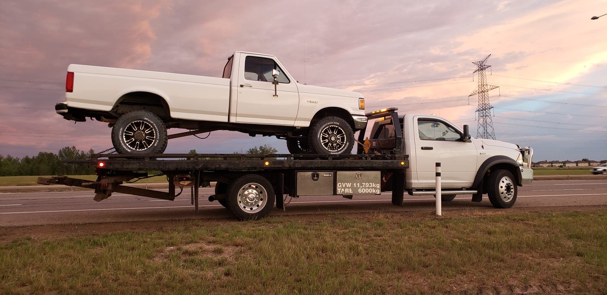 Tow truck carrying a pickup truck at sunset in Edmonton